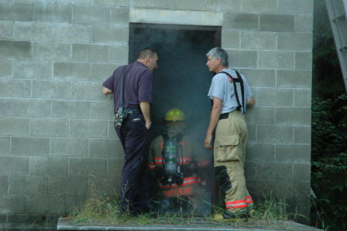 Firemen at the door of a smoky building
