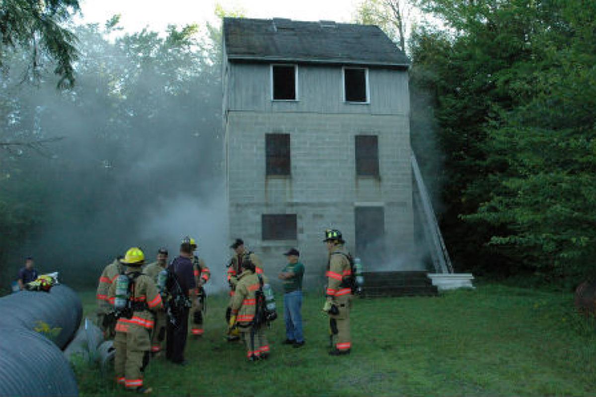 Firemen next to a burning house