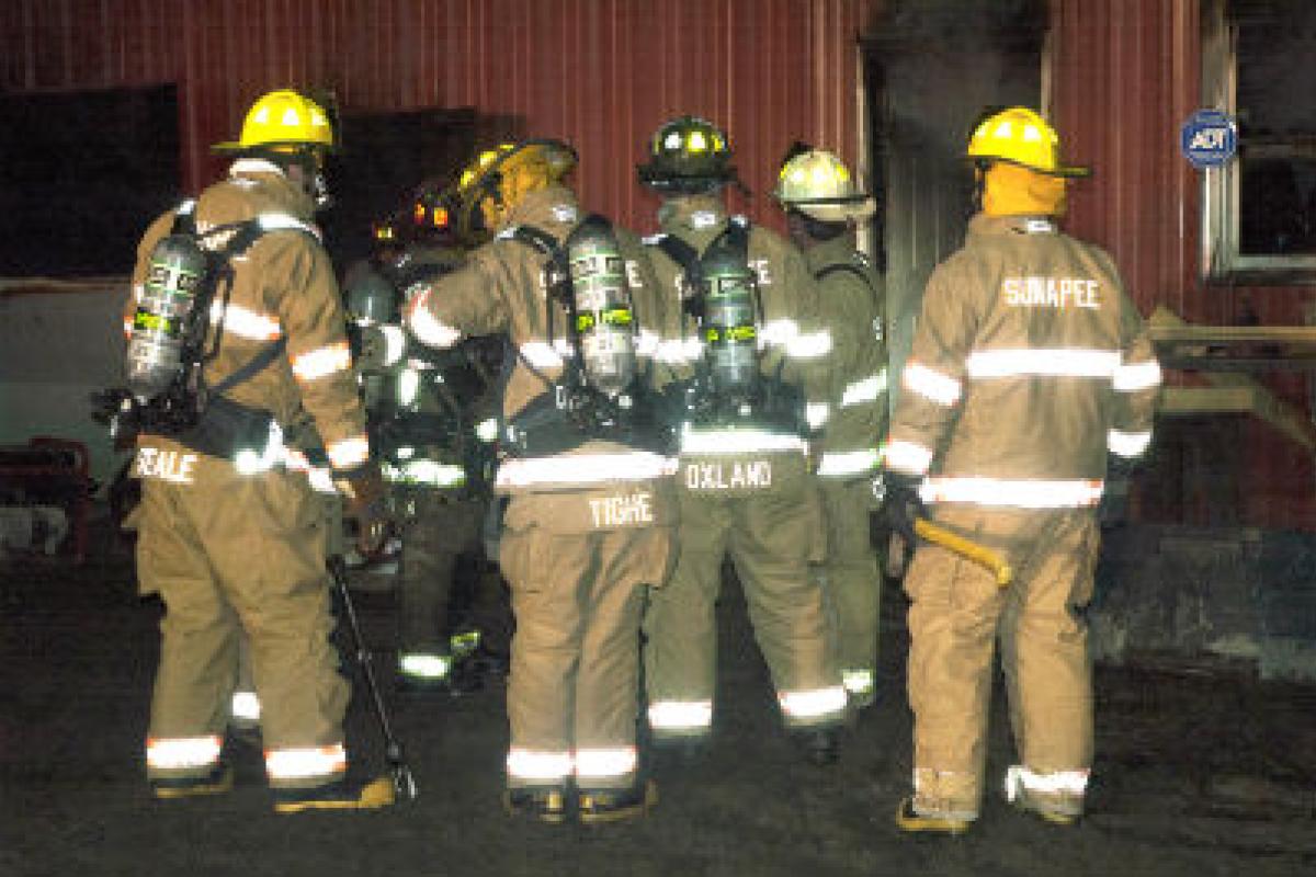 Firemen in gear in front of a building